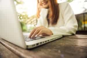 Woman in a white sweater on a computer during an online therapy session for anxiety with a Synergy eTherapy counselor.