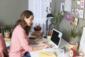 woman sits at her desk in her home chatting with an online therapist during online therapy with Synergy eTherapy