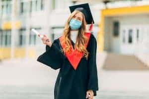 Happy graduate wearing a mask. She meets with an online therapist to get help dealing with grief. Learn more about online grief counseling from Synergy ETherapy here!