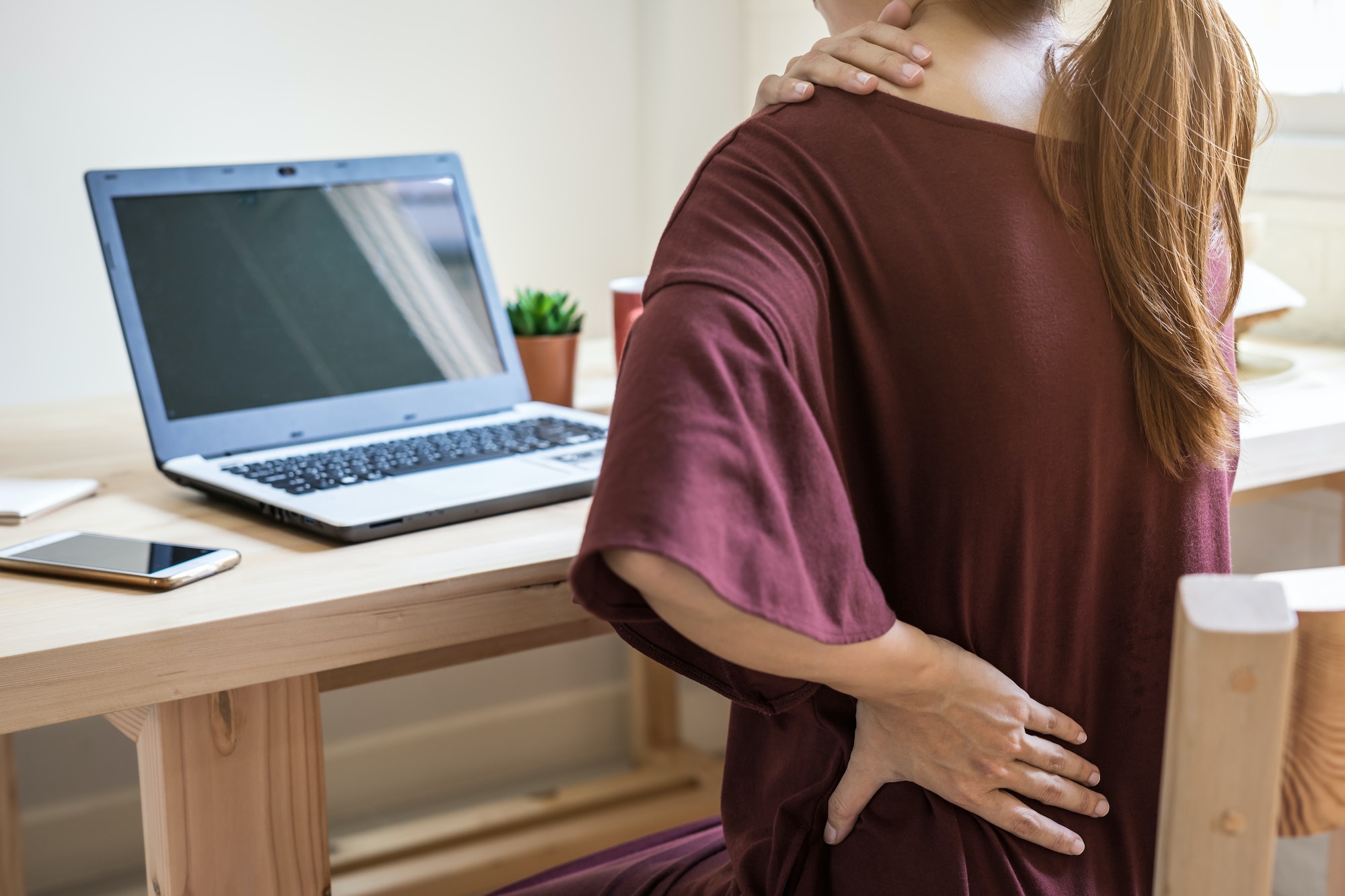 young woman working at home and having back pain